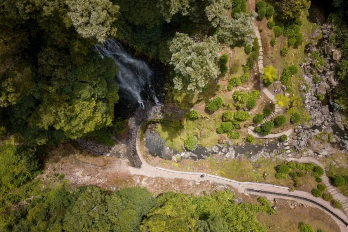 Aerial view of the Ribeira dos Caldeirões waterfall plunging into a lush green canyon park, São Miguel, Azores